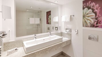 Un baño moderno con un espejo grande, dos lavamanos y un secador de pelo en la encimera.