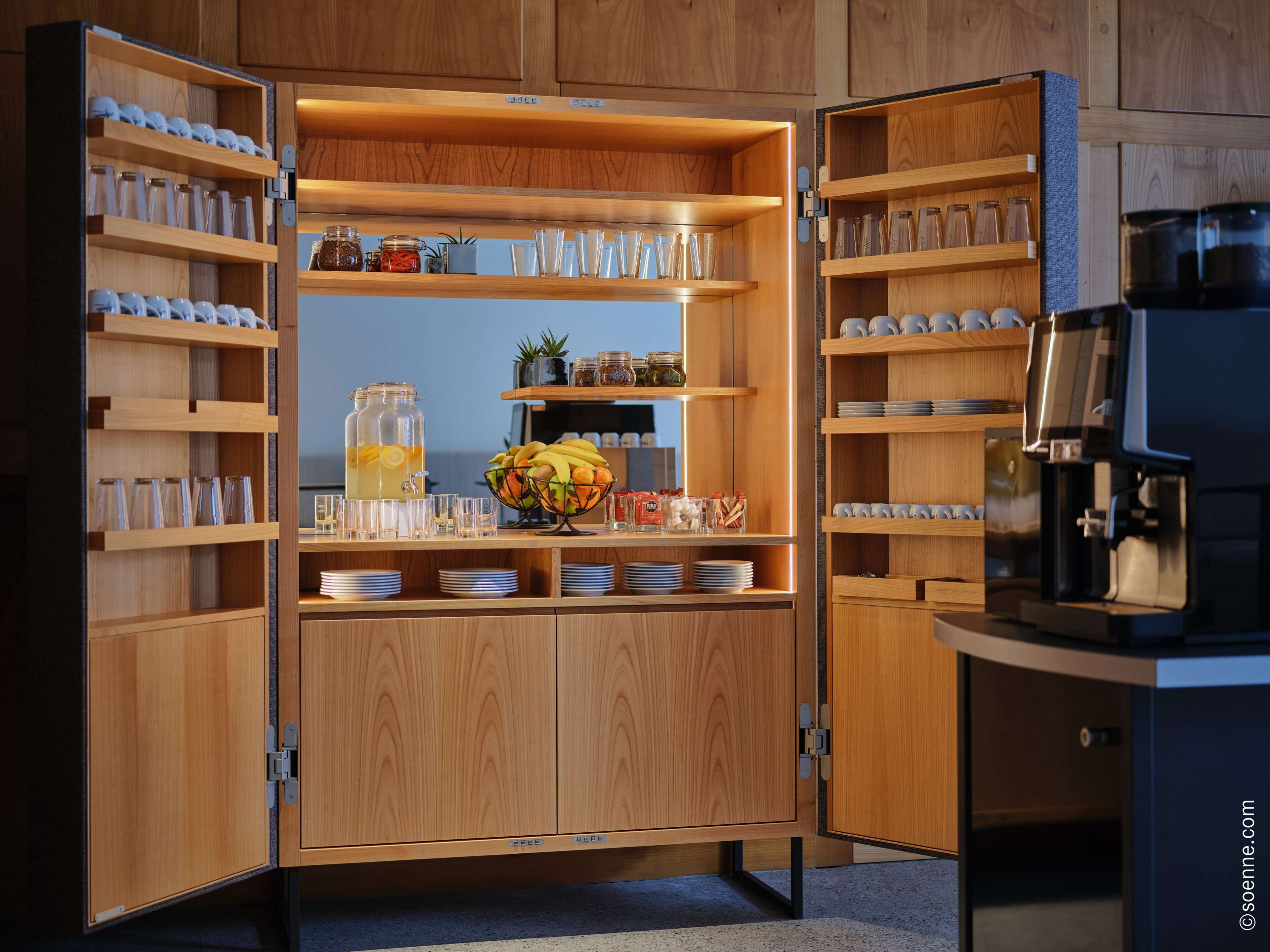 A modern kitchen with wooden cabinetry, open shelves, and a coffee machine.