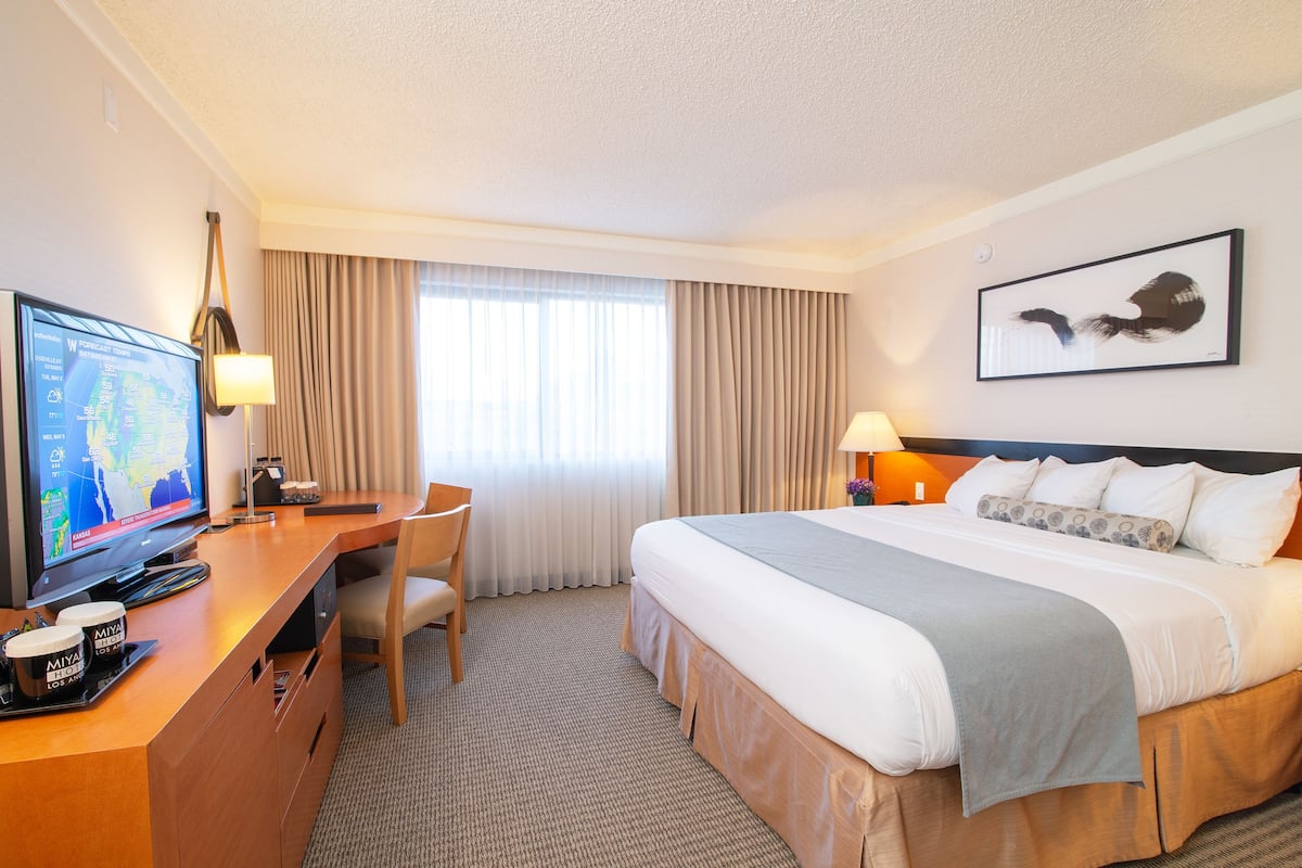 A hotel room with a bed, a desk with a computer, a chair, and a television.
