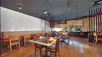 A restaurant with wooden flooring, tables, and chairs.