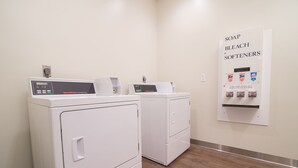 Un espace buanderie équipé de deux lave-linge et deux sèche-linge à chargement frontal, d’un distributeur de lessive et d’adoucissant, et d’un sèche-linge à réglage de la vitesse.