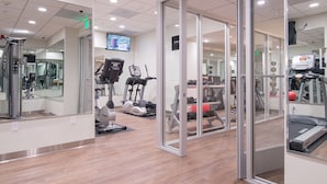 Une salle de sport moderne équipée d’appareils de cardio, de machines de musculation et dotée d’un mur entièrement recouvert de miroirs.