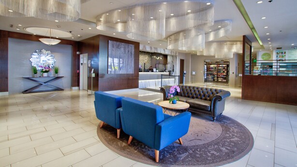 Un hall d’entrée spacieux, avec un canapé bleu, une table basse ronde et un lustre.