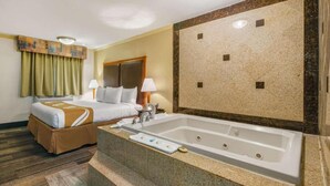 Habitación de hotel con una cama grande, baño independiente con bañera y piso alfombrado.