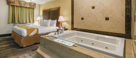 Ein Hotelzimmer mit einem großen Bett, einem separaten Badezimmer mit einer Badewanne und einem Teppichboden.