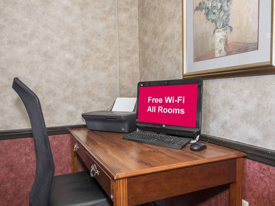 A hotel room with a desk, a laptop, and a sign indicating free Wi-Fi availability.