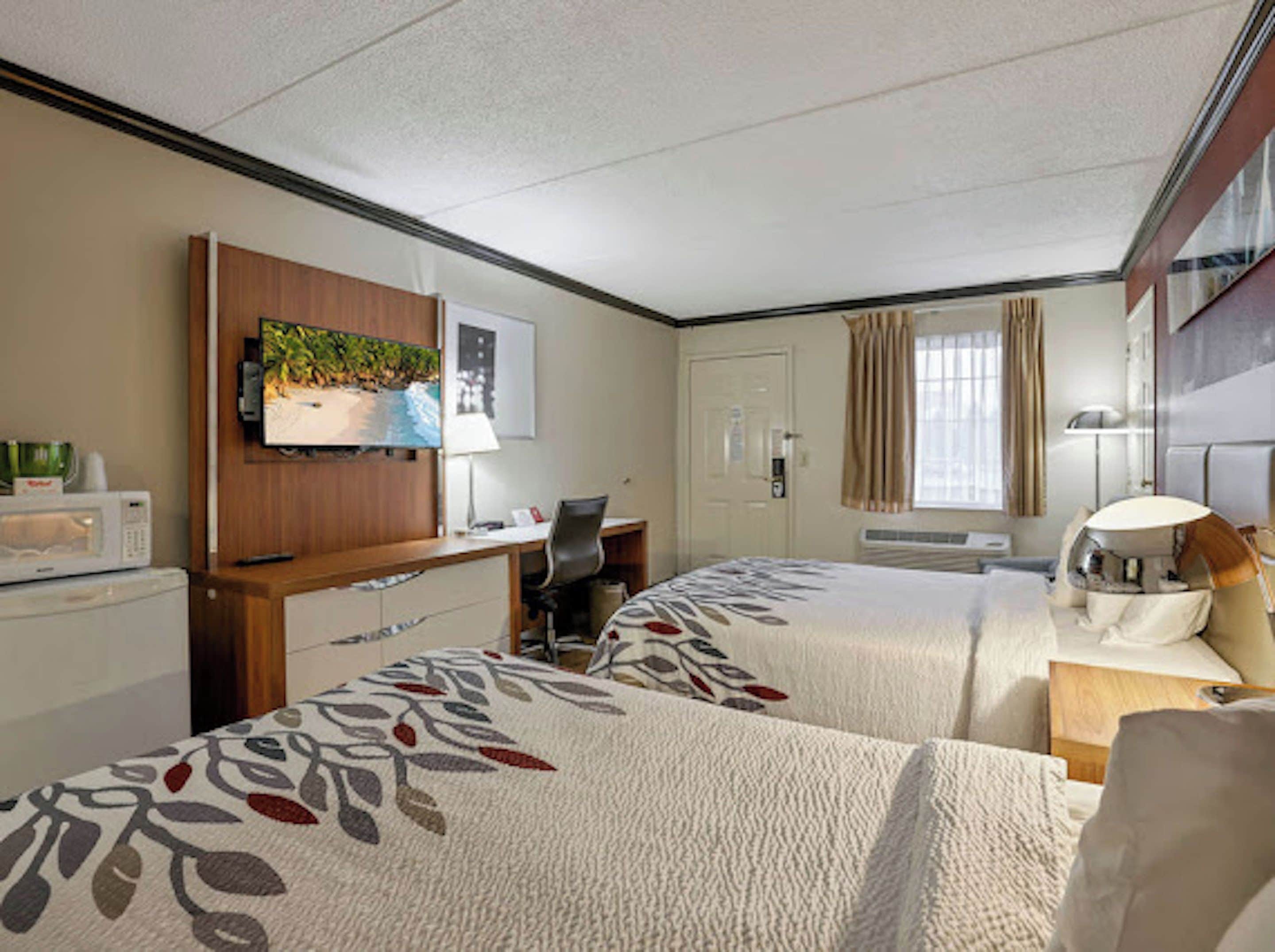 Een hotelkamer met twee bedden, een bureau, een televisie en een magnetron.