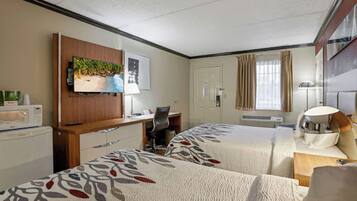 A hotel room with two beds, a desk, a television, and a microwave.