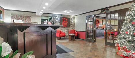 A reception area with a wooden reception desk, red chairs, a Christmas tree, and a wall with a sign.
