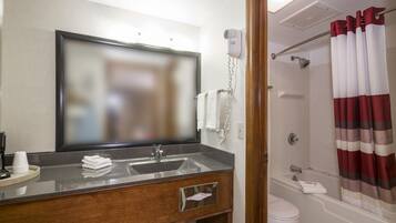 A bathroom with a sink, mirror, towel rack, shower, and toilet.
