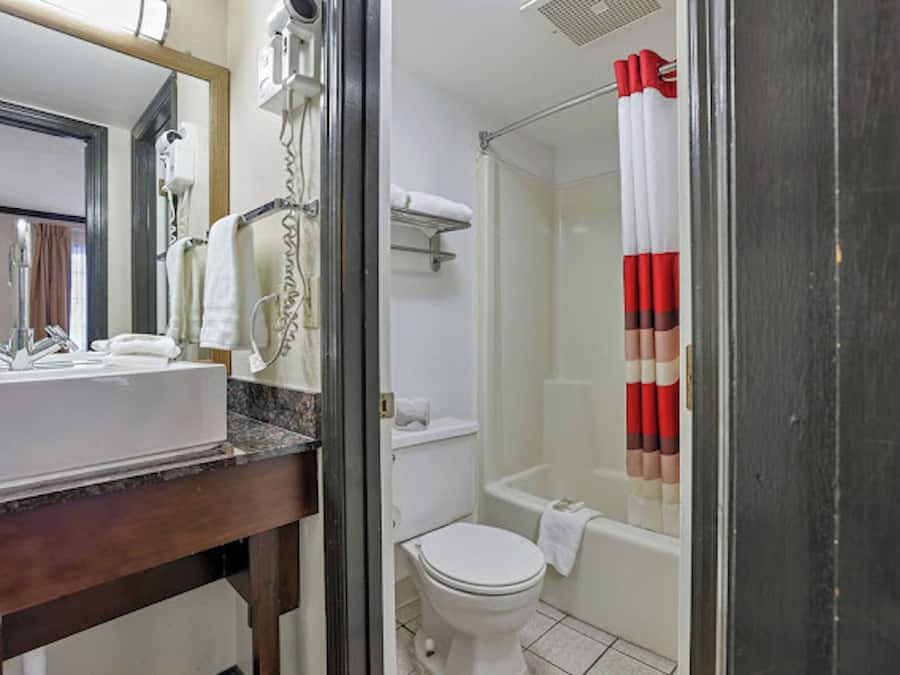 A bathroom with a sink, mirror, towel rack, shower, and toilet.