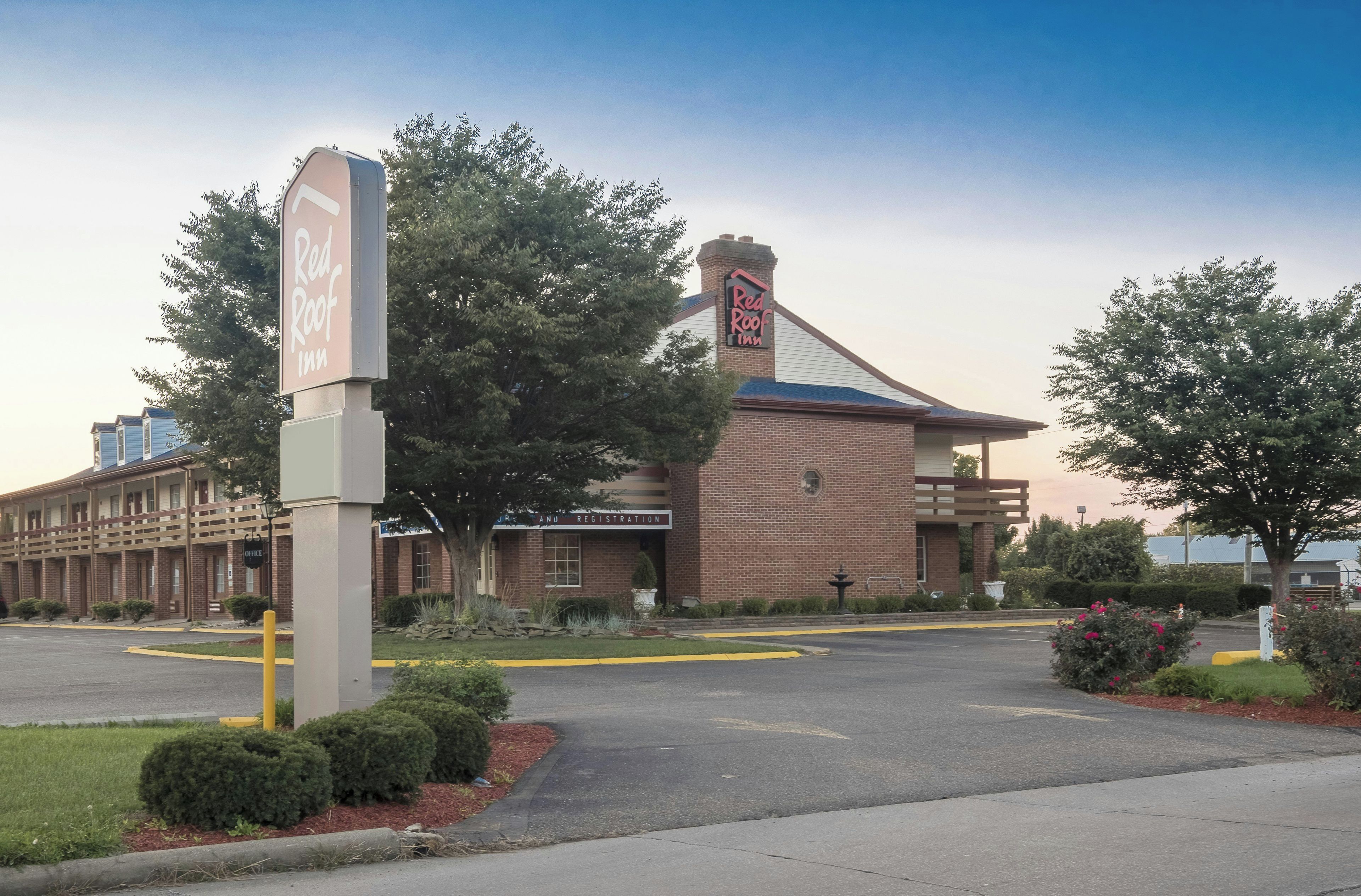 Un hotel Red Roof Inn con un edificio de ladrillo, una zona de recepción y un estacionamiento.
