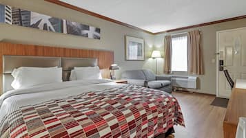 A hotel room with a large bed, a sofa, a desk, and a window with curtains.
