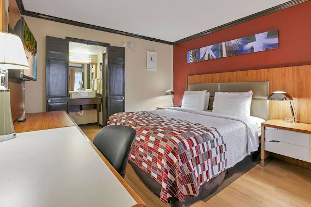 A hotel room with a bed, bedside tables, a desk, and a chair.