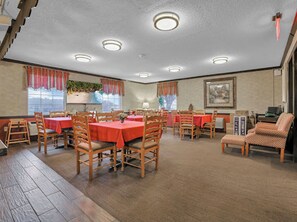 A dining area with multiple tables and chairs, a staircase, and a painting on the wall. - Red Roof Inn Uhrichsville (Uhrichsville)