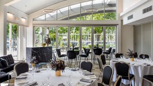 Un restaurante con techo alto, ventanas amplias y mobiliario moderno.