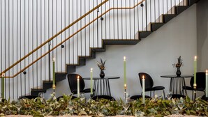 A dining area with a staircase, tables set with candles, and greenery. - Terrace Hotel Adelaide (Adelaide)