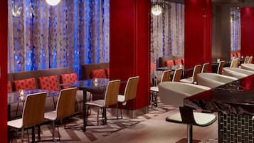 Un ristorante moderno con tavoli e banconi in vetro, dettagli rossi e tende a motivi.