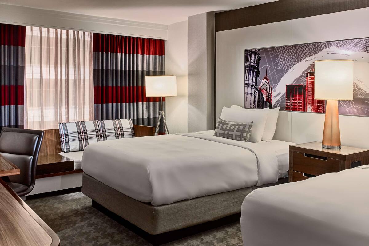Une chambre d’hôtel avec un grand lit, un bureau, une chaise et une table de chevet avec une lampe.