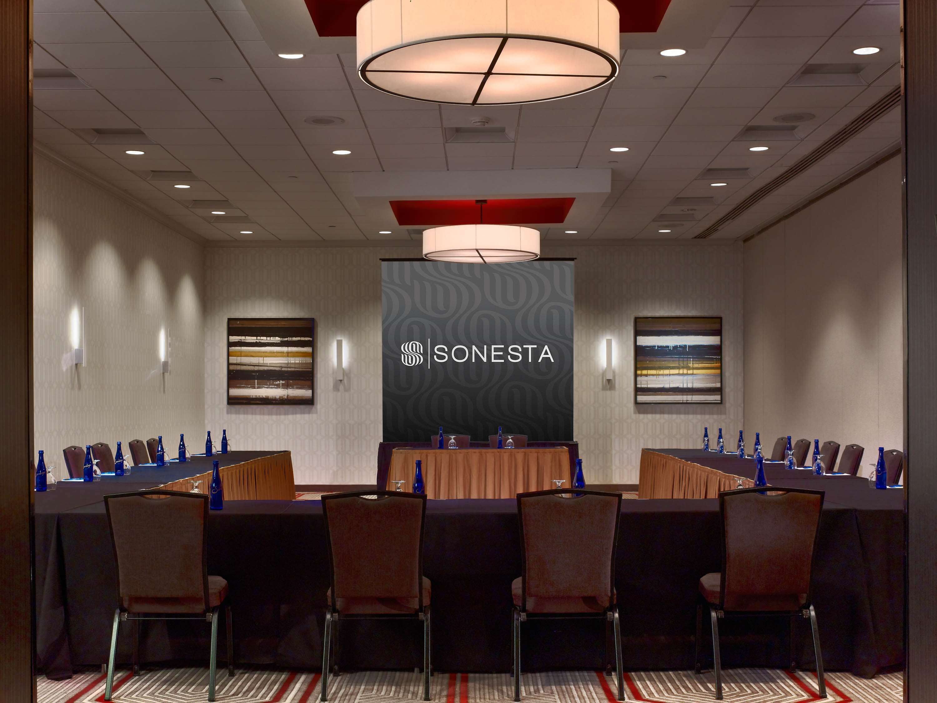 A conference room with a long table, chairs, and a SONESTA banner.