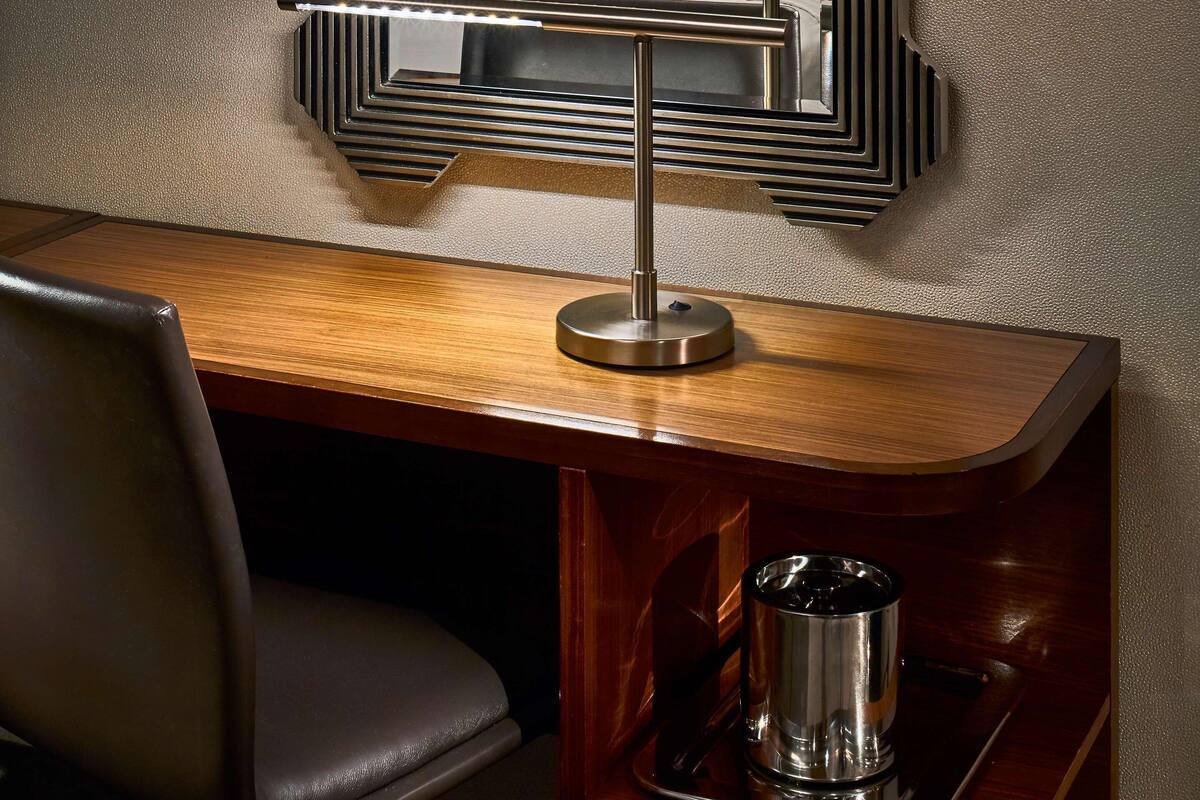 Une chambre d’hôtel moderne, dotée d’un grand miroir, d’un bureau en bois, d’une chaise et d’une machine à café.