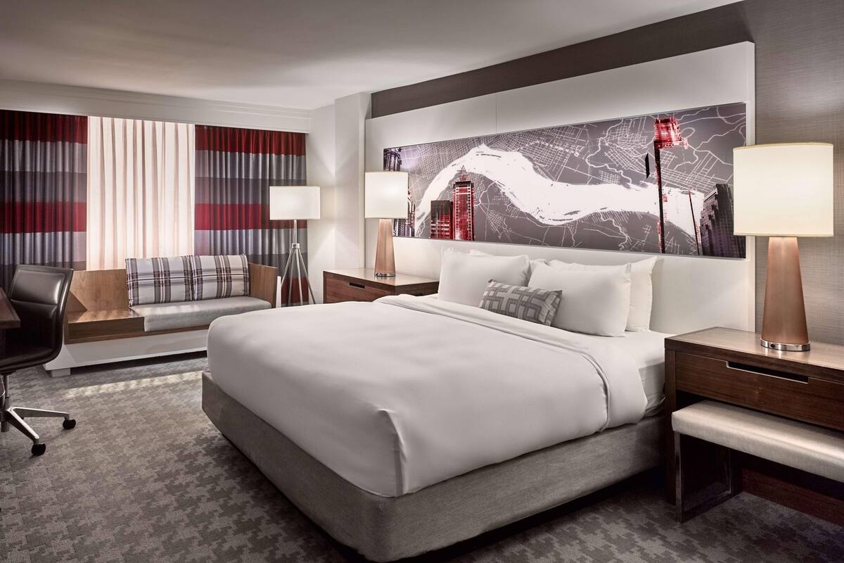 Une chambre d’hôtel moderne équipée d’un grand lit, d’un canapé, d’un bureau et d’une carte murale.