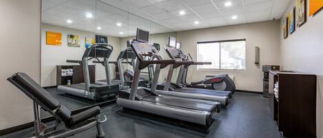 A gym with treadmills, a weight bench, and a mirrored wall.