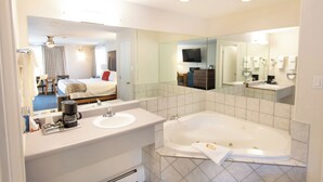 Ein modernes Badezimmer mit großem Spiegel, einer Badewanne, einem Waschbecken und einer Kaffeemaschine.