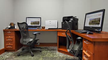 Un bureau moderne équipé de deux ordinateurs de bureau, d’une imprimante et d’un fauteuil de bureau noir.