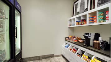 Un pequeño bar de aperitivos bien organizado, con estantes llenos de diferentes opciones y una máquina de café.