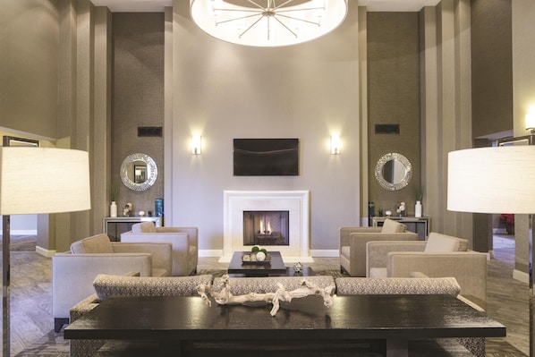 Un vestíbulo amplio con chimenea, zona de estar y espejos decorativos.