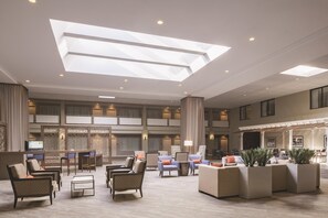 A spacious lobby with a high ceiling, multiple seating areas, and a central column. - DoubleTree by Hilton Hotel Laurel (Laurel)