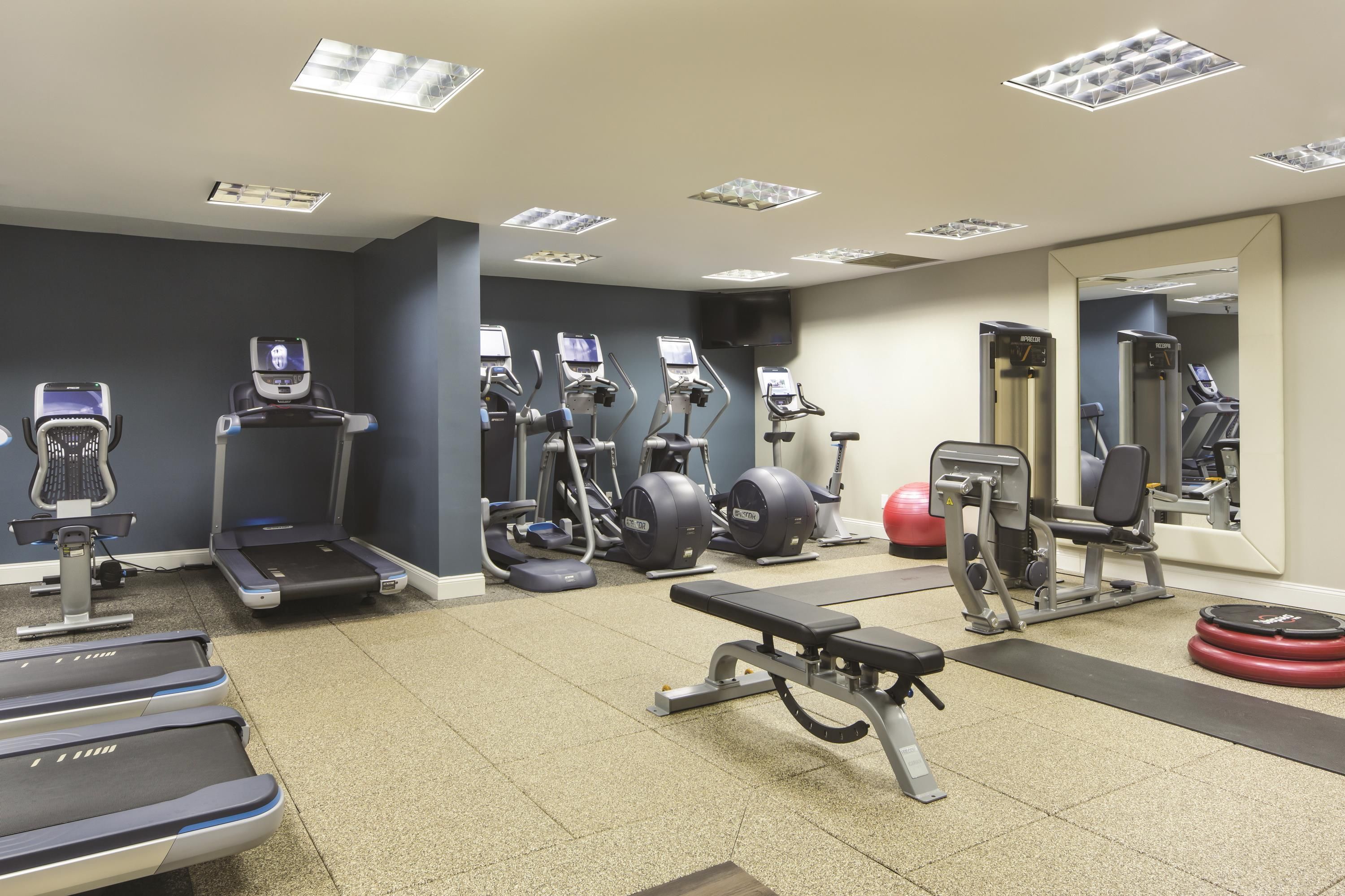 Un gimnasio con cintas de correr, elípticas y equipo de pesas.