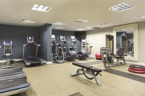Un gimnasio con cintas de correr, elípticas y equipo de pesas.