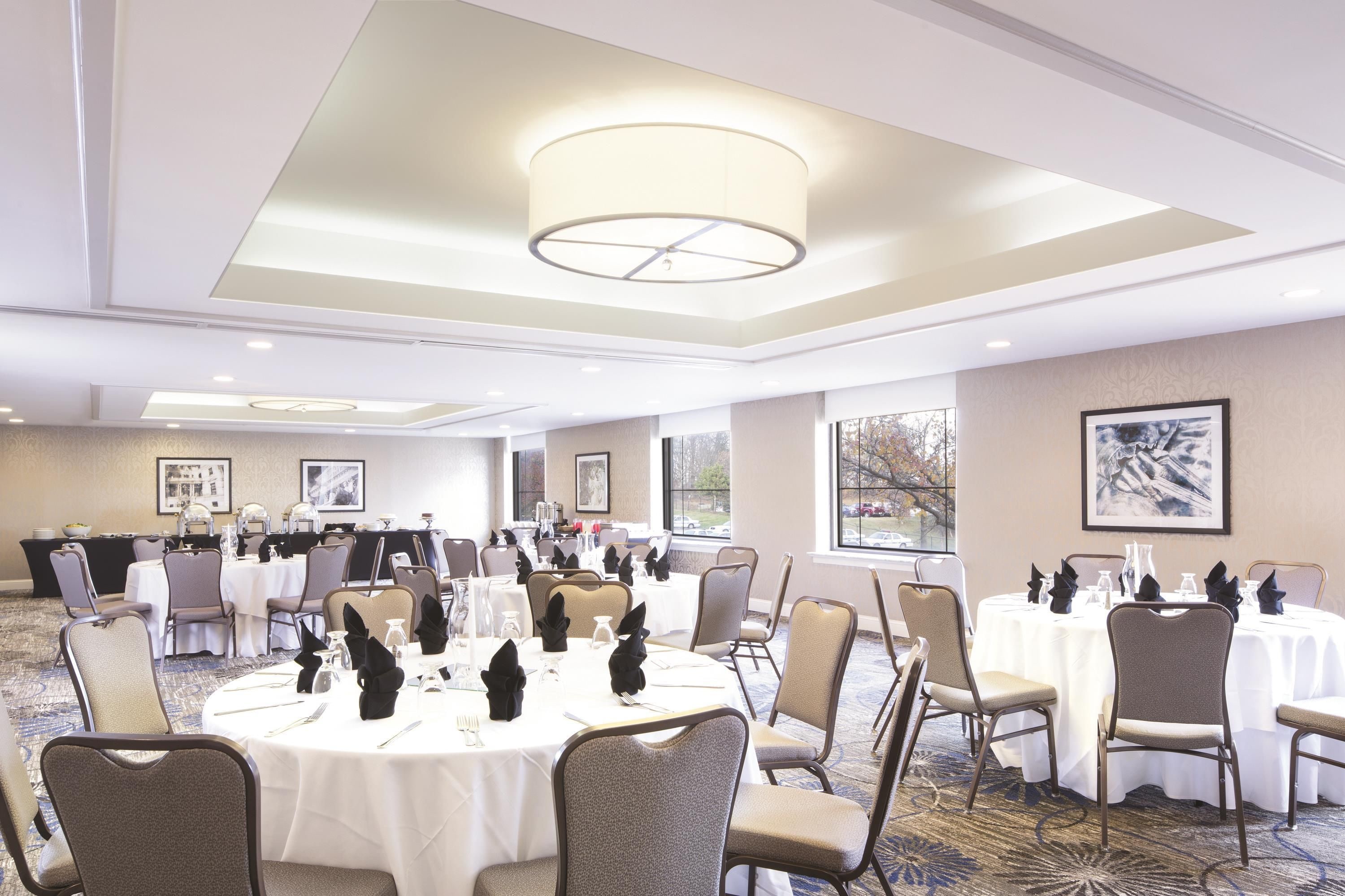 Une salle de conférence équipée de tables rondes, de chaises et d’un luminaire au plafond.