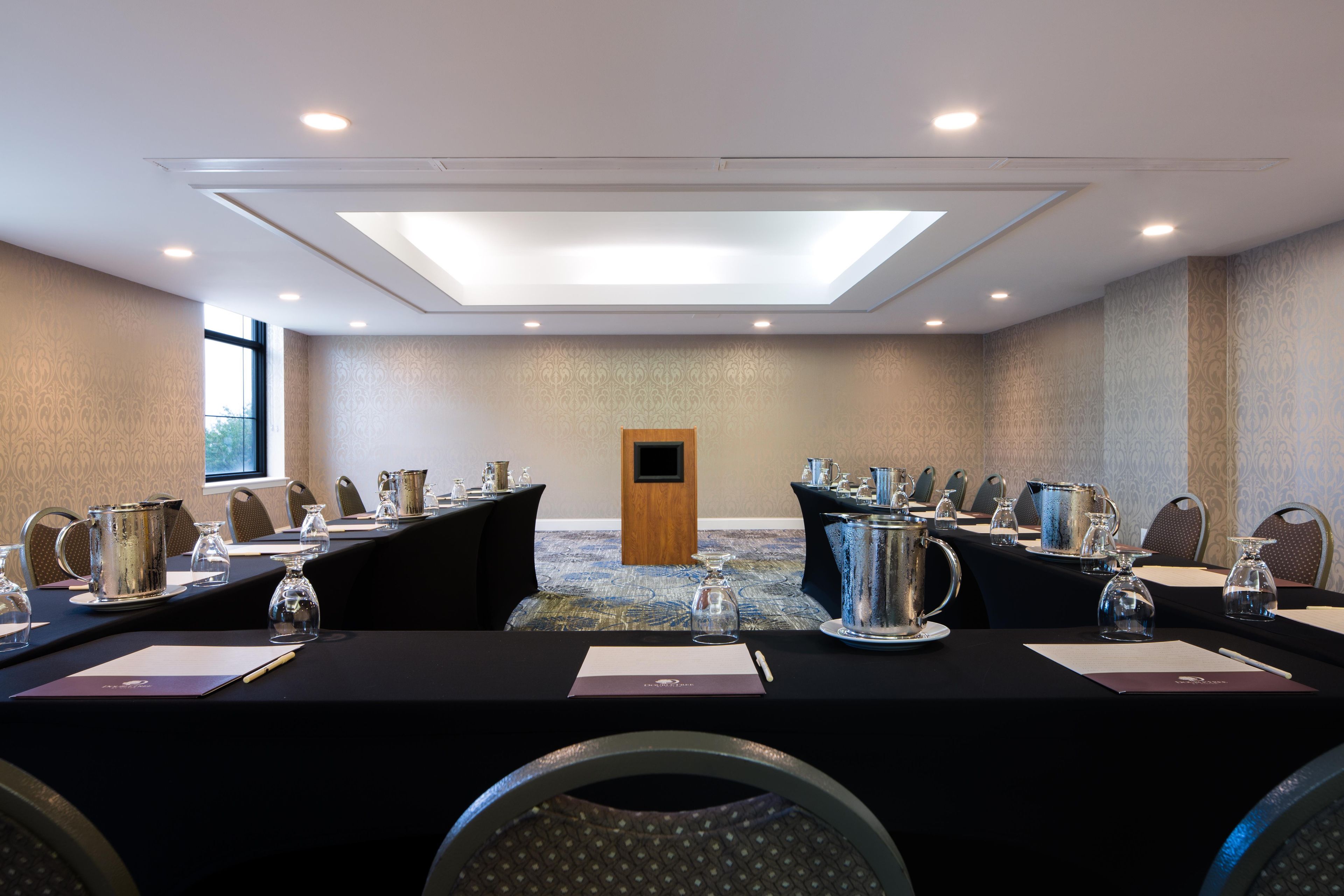 A conference room with a long table, chairs, and a television screen.