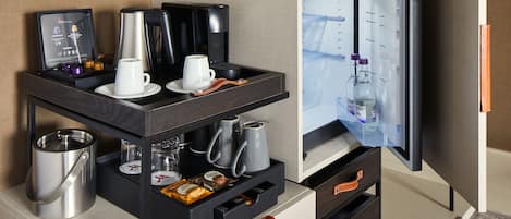 A hotel room with a minibar, a coffee maker, a kettle, and a refrigerator.