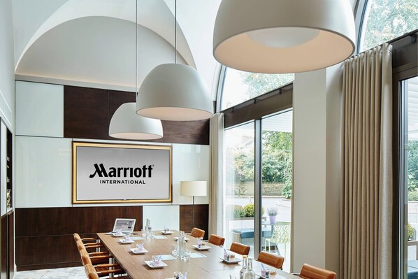 Un salón de conferencias de Marriott International con una larga mesa, sillas y lámparas colgantes.