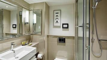 A modern bathroom with a large mirror, a sink, a toilet, and a shower.