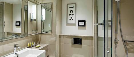 A modern bathroom with a large mirror, a sink, a toilet, and a shower.