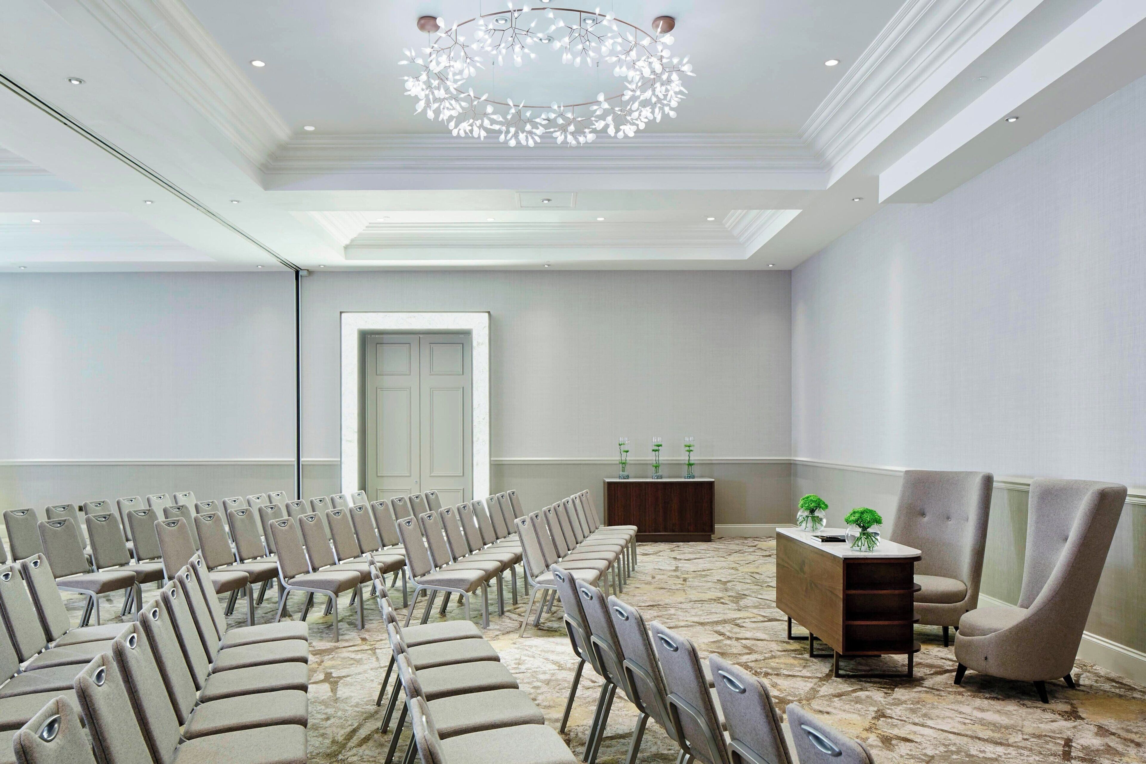 A conference room with rows of chairs, a podium, and a chandelier.