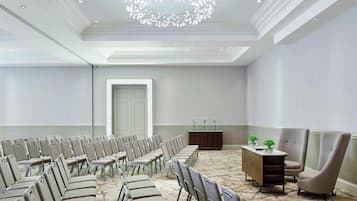A conference room with rows of chairs, a podium, and a chandelier.