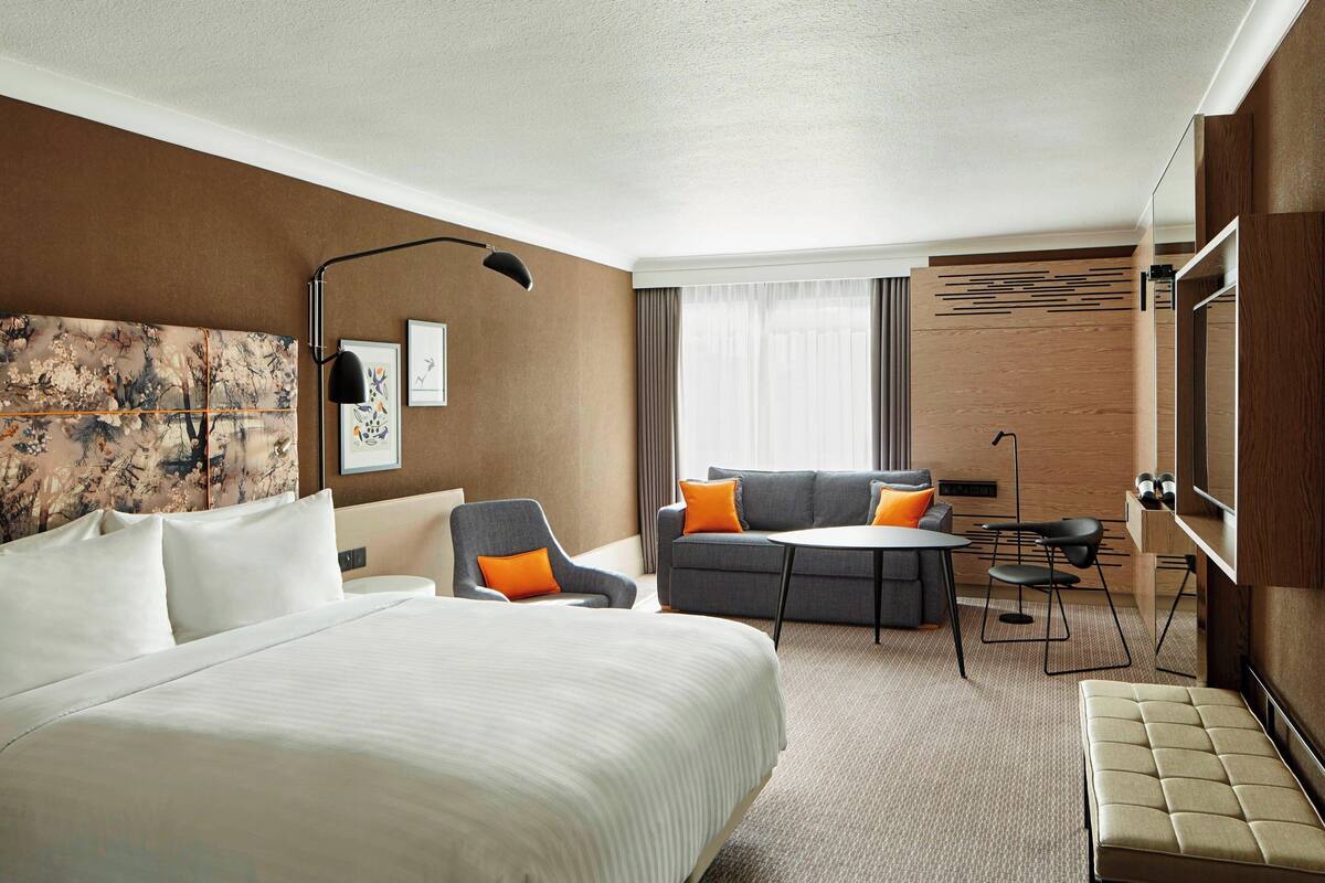 Ein Hotelzimmer mit einem großen Bett, einer Couch, einem Schreibtisch und einem Fernseher.