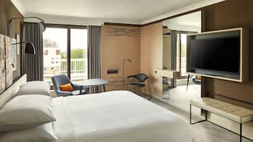 Une chambre d’hôtel avec un grand lit, une télévision, un bureau et un balcon donnant sur les immeubles.