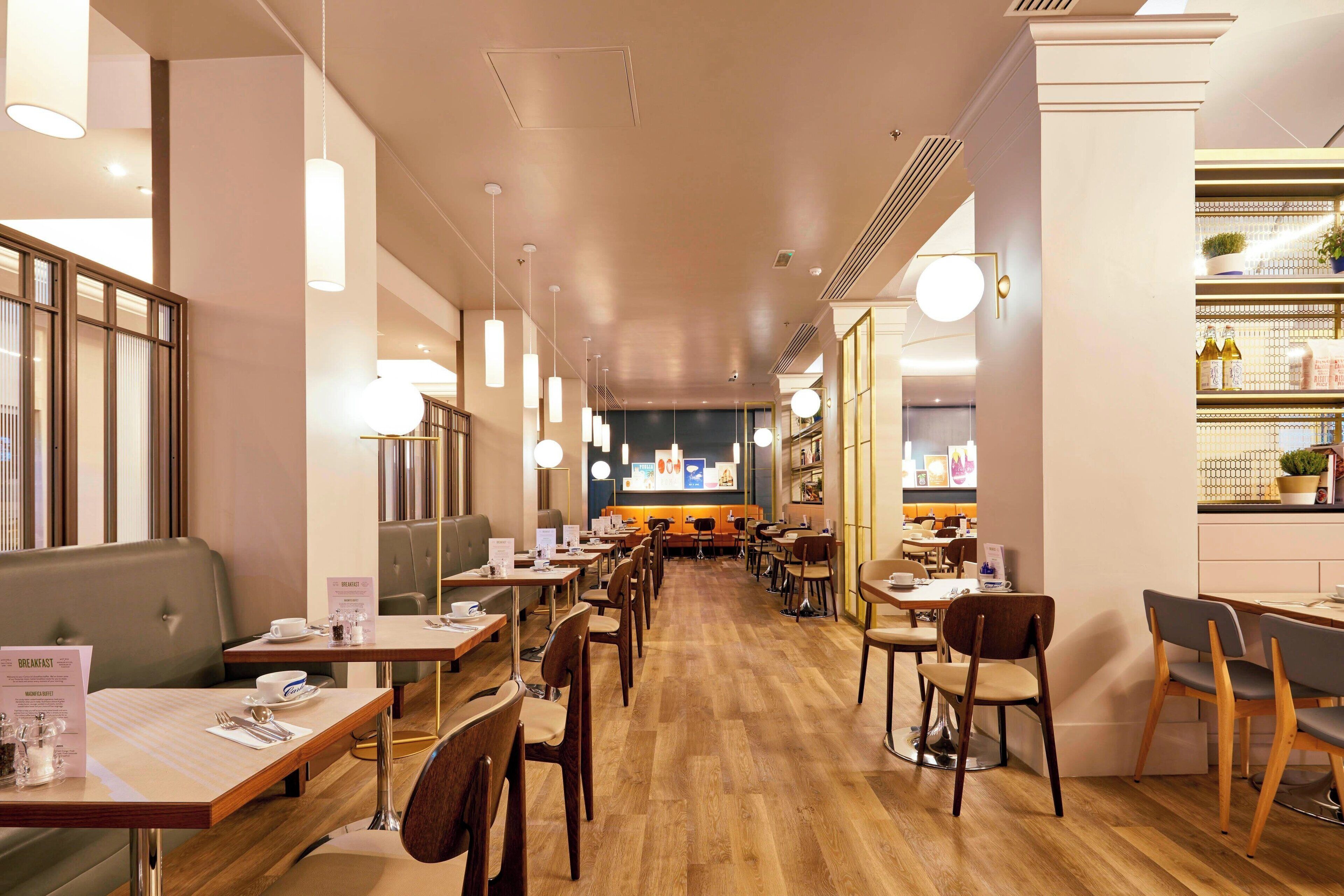 Ein Restaurant mit Holzboden, mehreren Tischen und Stühlen, Pendelleuchten und einer Theke mit verschiedenen Artikeln.