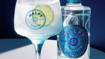 A clear glass with a lime slice and a bottle of Malfy gin.