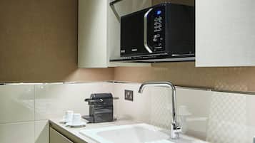 A modern kitchen with a built-in microwave, a coffee machine, and a sink with a faucet.