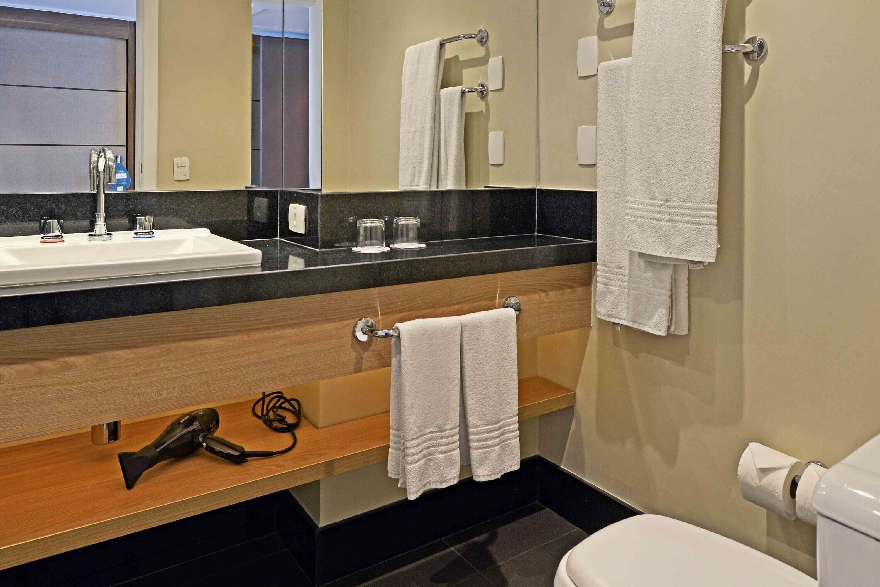 A bathroom with a sink, mirror, towel rack, and toilet.