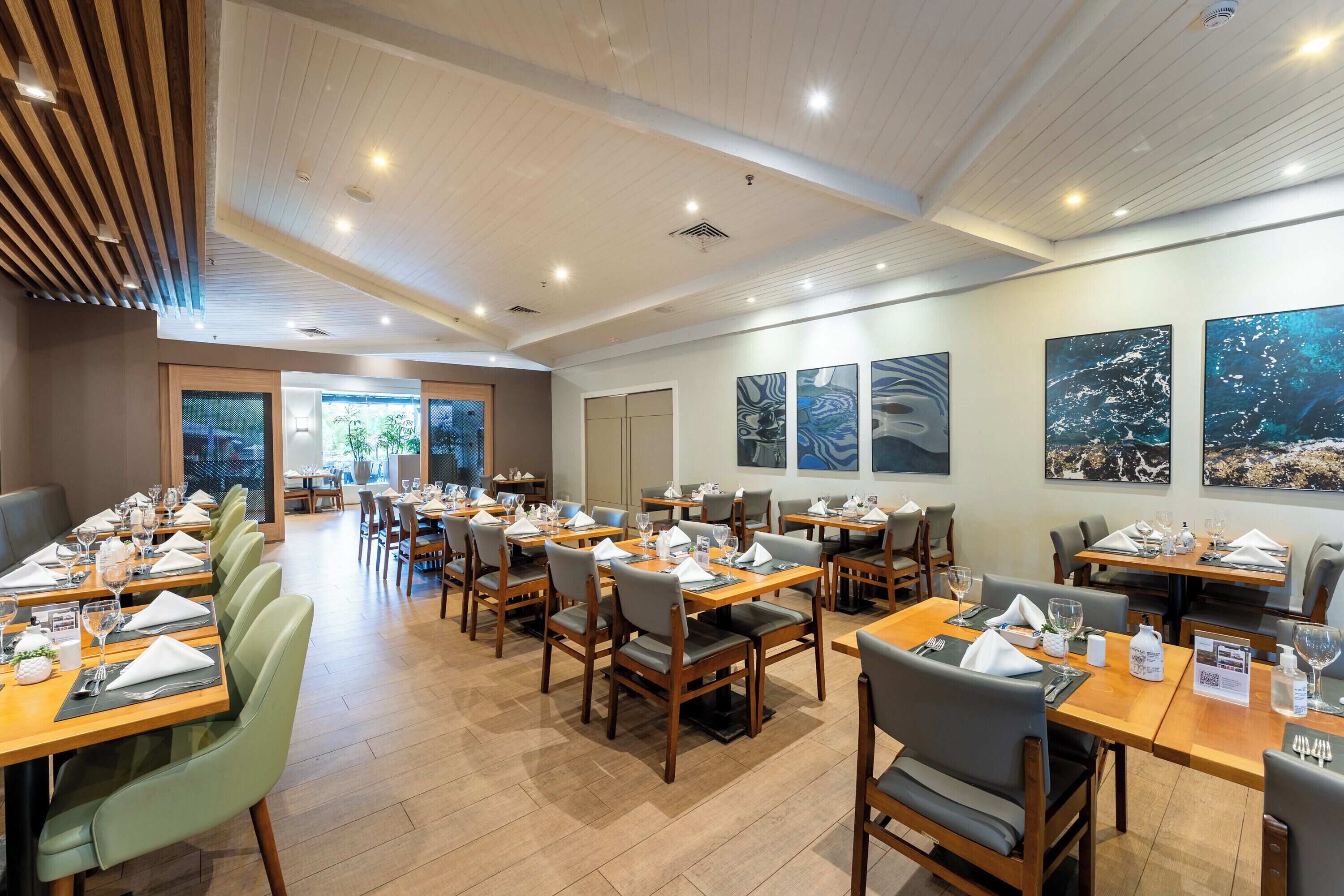 Um restaurante com várias mesas, cadeiras e obras de arte nas paredes.