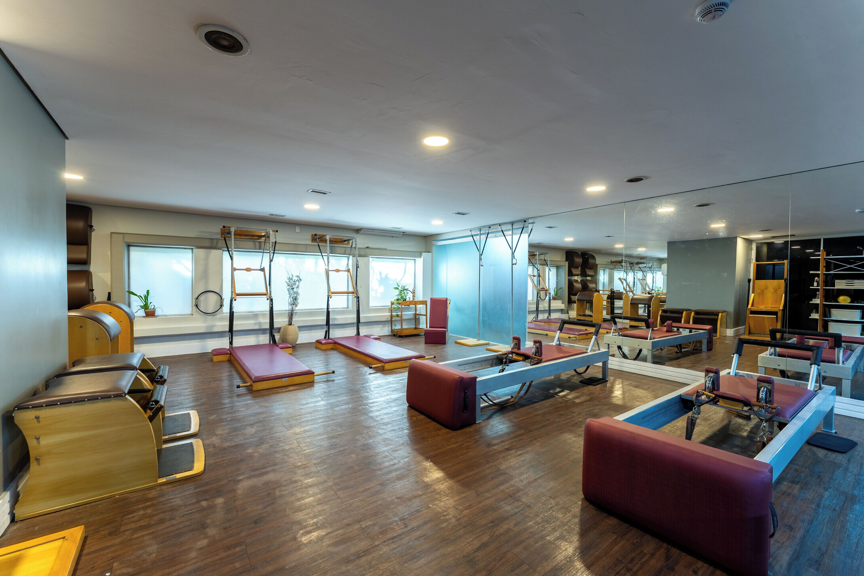 A spacious gym with various exercise equipment, including Pilates reformers and yoga mats.